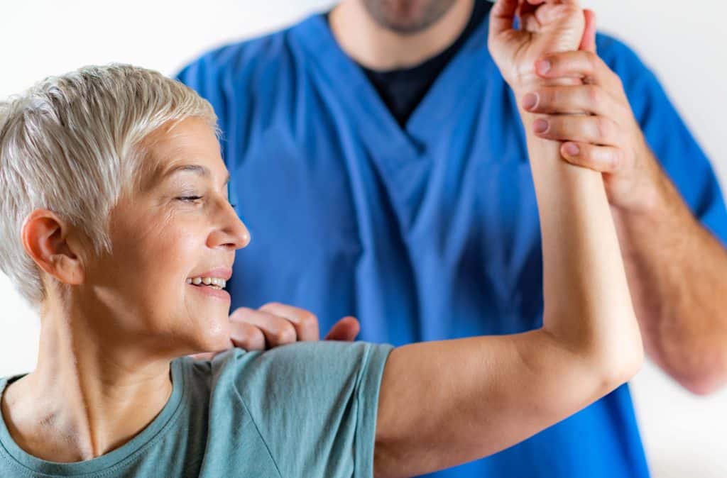 Therapist Checking Senior Woman’s Arm in Physical Therapy Office